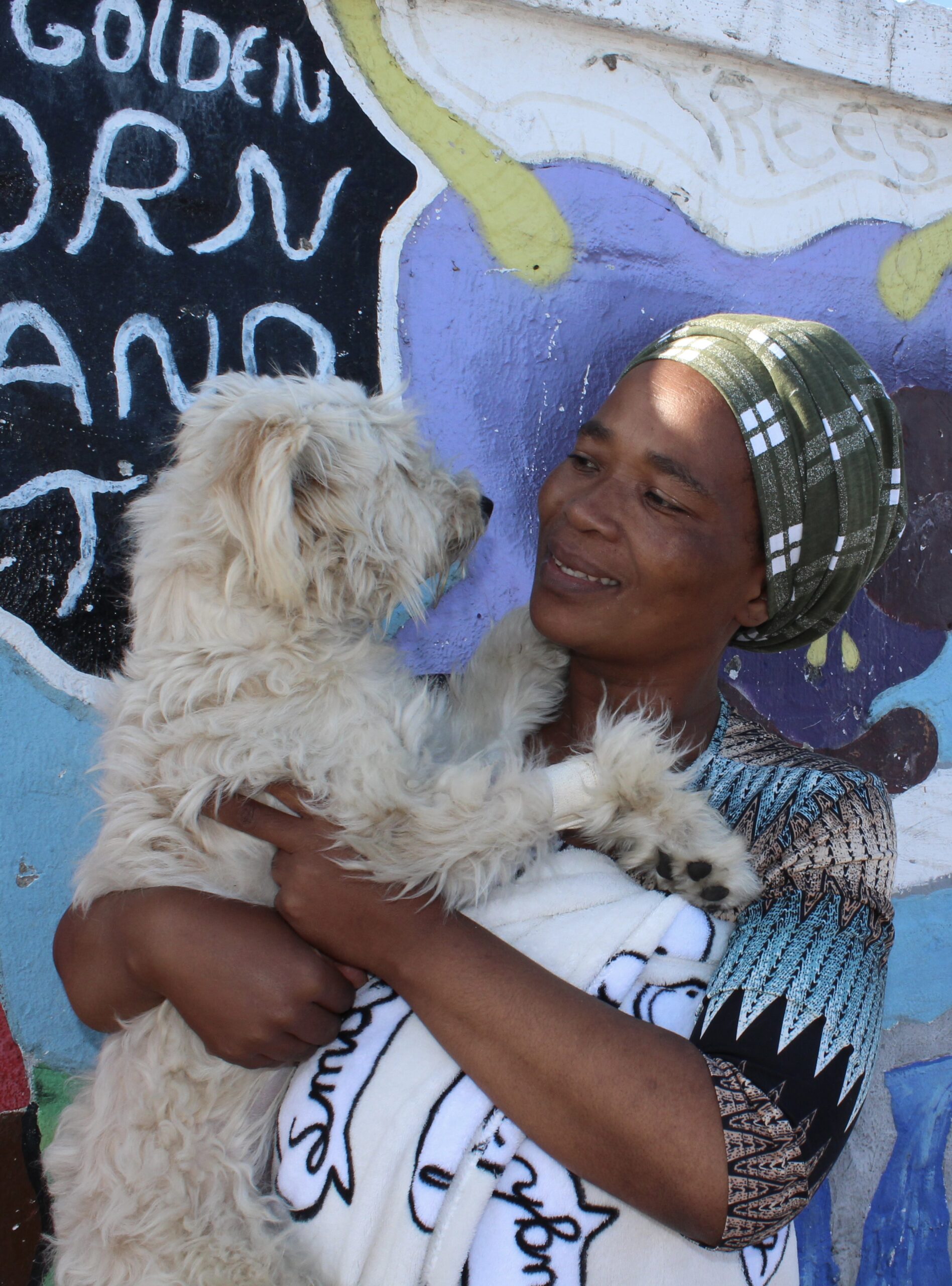 Woman smiling while holding her dog during an AfriPaw community programme.
