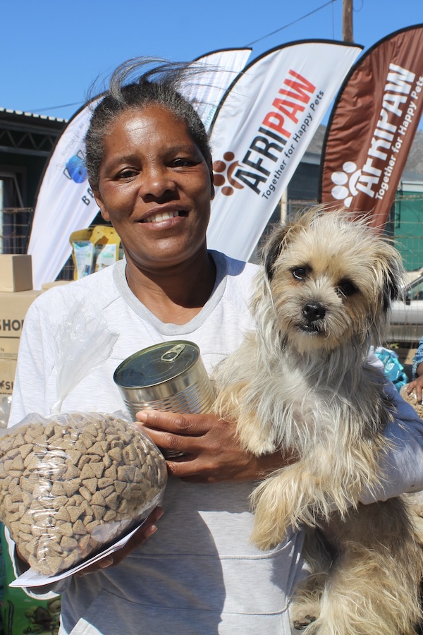 Pet owner holding her dog and pet food supplies during an AfriPaw community outreach programme.