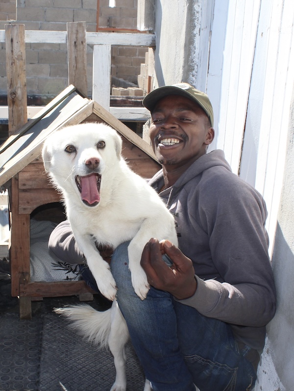 Community member smiling with his dog after receiving a kennel supported by AfriPaw.